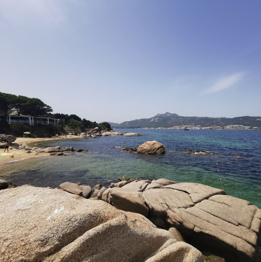 Felsen und Sandstrand mit einer Strandbar im Hintergr